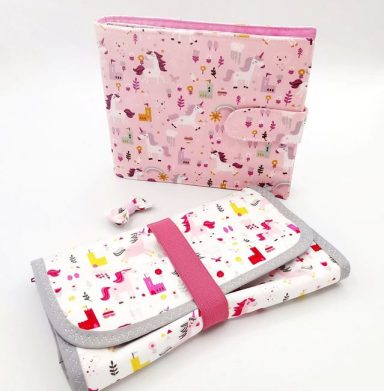 une trousse de médicaments et album photo en tissu à motifs colorés sur fond rose.